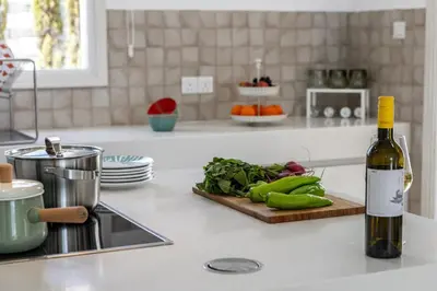a bottle of wine and a cutting board with vegetables on a kitchen counter at Protaras Sunrise Zen Seafront Villa in Protaras