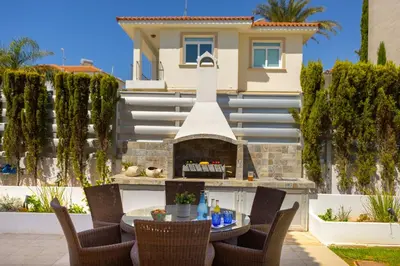 a patio with a table and a fireplace in front of a house at Protaras Sunrise Zen Seafront Villa in Protaras
