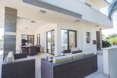 a patio with wicker furniture and a dining area at Demetra Villa in Ayia Napa
