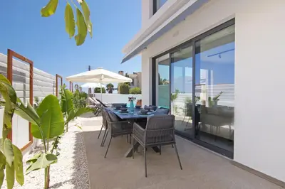 a table with chairs and an umbrella on a patio at Votsalo Villa - 30m from Med Sea in Ayia Napa