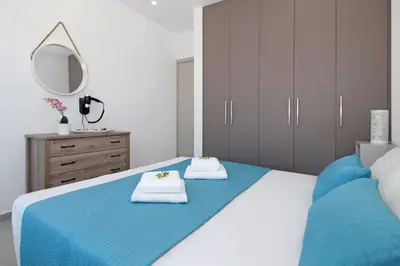 a bedroom with a blue bed with towels and a mirror at Votsalo Villa - 30m from Med Sea in Ayia Napa
