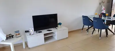 a living room with a television and a table with chairs at Nissi 3 Pool View Apartment in Ayia Napa