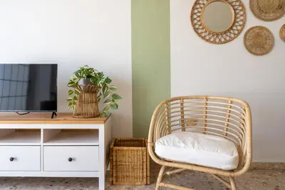 a rattan chair sitting next to a tv and a desk at Blossom 1-Bedroom Apartment in Larnaca in Larnaka