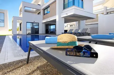 a hat and sunglasses sitting on a table next to a swimming pool at Villa Amazonia - Large Private Pool in Protaras