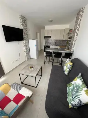a living room with a black couch and a kitchen at Stay With Oleg C111 in Paralimni
