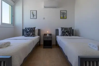 two twin beds in a room with a table at Chloris 3- Bedroom Apartment W/Pool in Larnaca in Larnaka