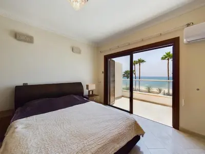 a bedroom with a bed and a view of the ocean at Fabulous beach front house with pool in Larnaka