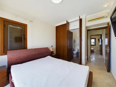 a bedroom with a white bed and a bathroom at Fabulous beach front house with pool in Larnaka
