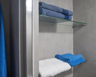 a bathroom with a glass shelf with towels at Lovely Studio by the Beach in Voroklini
