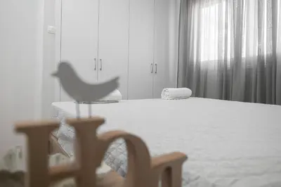a white bedroom with a bed and a chair at Lovely Studio by the Beach in Voroklini