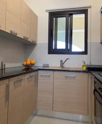 a kitchen with wooden cabinets and a sink and a window at Quiet kykladesAG10/near the beach, Paralimni in Paralimni