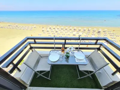 a table and chairs on a balcony with a beach at Beach Serenity Studio on Makenzy in Larnaka