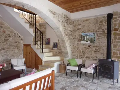 a room with a stone wall and stairs with a wood stove at The House of Pericles in Silikou