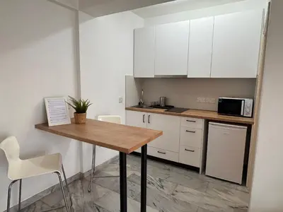 a kitchen with a wooden table and white cabinets at Nicosia Downtown Cozy in Nicosia
