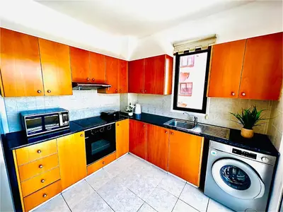 a kitchen with wooden cabinets and a washing machine at Mackenzie apartment 301 in Larnaka