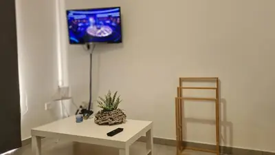 a living room with a white table and a tv on a wall at STAY Sand Flat in Paralimni