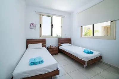 two beds in a room with two windows at Villa Anna Maria, Kapparis in Paralimni