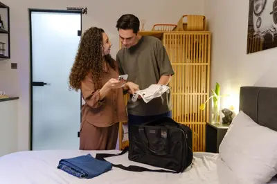 a man and woman looking at a cell phone next to a bed at Fat Cow Apartments in Larnaka