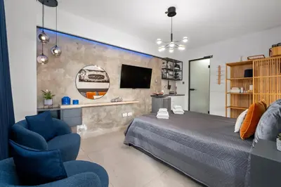 a bedroom with a bed and a chair and a tv at Fat Cow Apartments in Larnaka