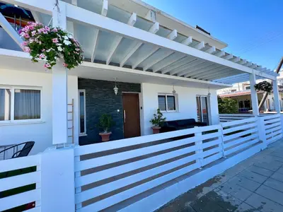 a white fence with a pergola on a house at Fat Cow Apartments in Larnaka