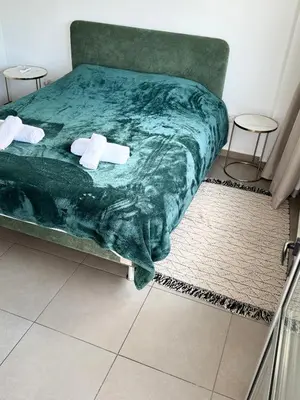 a bed with a green blanket and two stools on it at Anastasia 1 Bedroom Apartment in Limassol