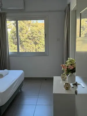 a room with a bed and a table with flowers on it at Anastasia 1 Bedroom Apartment in Limassol