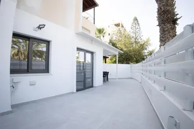 a white house with white walls and a walkway at Phaedrus Living: Luxury Mackenzie Flat in Larnaka