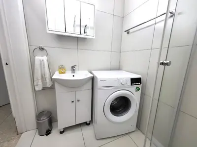 a small bathroom with a washing machine and a sink at Mattis Seafront Beachhouse in Pervolia