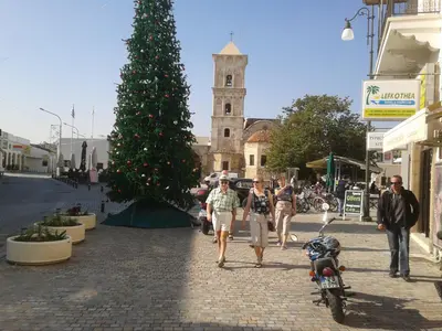 a group of people walking down a street with a christmas tree at St. Lazaros Seaside Apartment in Larnaka