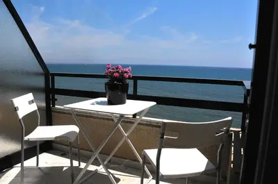 a table and chairs on a balcony with the ocean at Stadem Studios in Larnaka