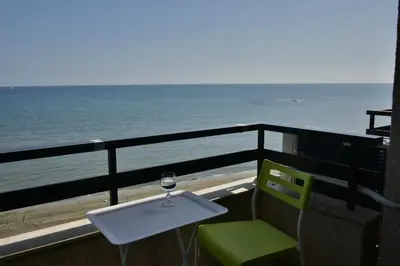 a glass of wine sitting on a balcony overlooking the ocean at Stadem Studios in Larnaka
