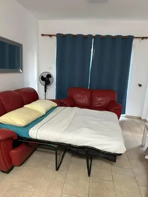 a bed in a living room with a red couch at Sidra's Apartment in Paralimni