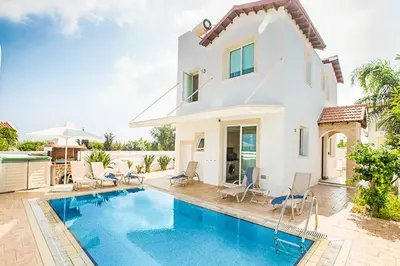 a villa with a swimming pool in front of a house at Villa Cayenne in Protaras