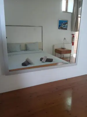 a mirror reflecting a bedroom with a bed and a table at Skarinou Village Poolside Escape Studio with Pool facilities in Skarinou