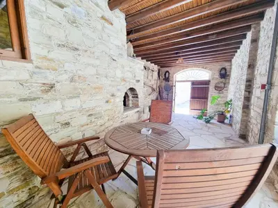 a patio with a table and chairs in a stone wall at Skarinou's Landhouse Poolside Heaven Apartment in Skarinou