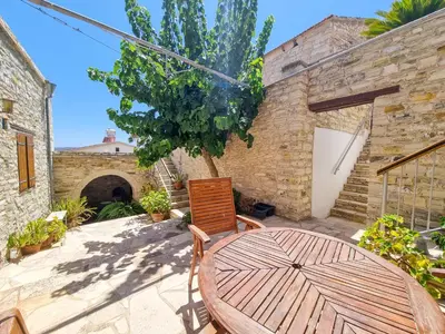 a patio with a wooden table and a tree at Traditional Village Pool Paradise Family Apartment in Skarinou