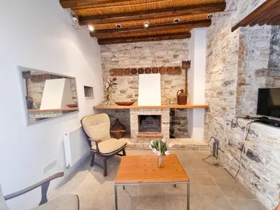 a living room with a stone fireplace and a table at Traditional Village Pool Paradise Family Apartment in Skarinou