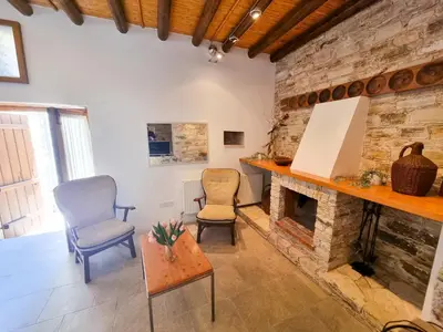 a living room with two chairs and a stone fireplace at Traditional Village Pool Paradise Family Apartment in Skarinou