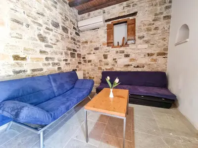 a living room with a blue couch and a table at Traditional Village Pool Paradise Family Apartment in Skarinou