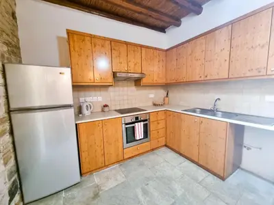 a kitchen with wooden cabinets and a white refrigerator at Traditional Village Pool Paradise Family Apartment in Skarinou