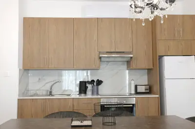 a kitchen with wooden cabinets and a sink and a table at Musan Boutique Apartments in Ayia Napa