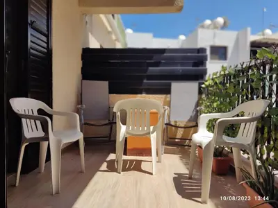 three chairs and a table on a balcony with a piano at Vicky apartment in Paralimni