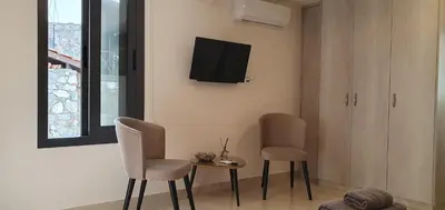 a living room with two chairs and a table and a tv at Chic Elegance Meets Village Gem in Pelendri