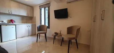 a kitchen with two chairs and a table and a television at Chic Elegance Meets Village Gem in Pelendri