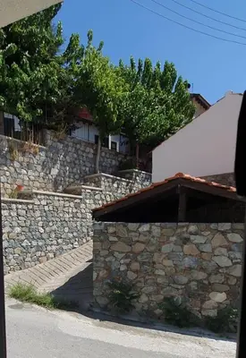 a stone wall next to a building at Chic Elegance Meets Village Gem in Pelendri