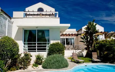 a white house with a swimming pool in front of it at Anastasia in Pissouri