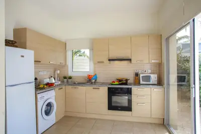 a kitchen with wooden cabinets and a white refrigerator at Villa Cliantha in Protaras