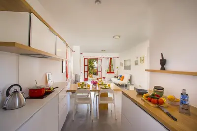 a kitchen with white cabinets and a table and chairs at Liora Suite in Protaras