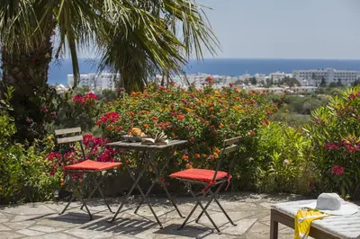 a table and chairs in front of some flowers at Liora Suite in Protaras
