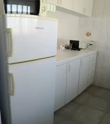 a kitchen with a white refrigerator and white cabinets at Julie's beach house in Voroklini